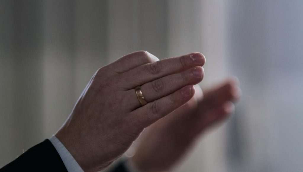 Close-up of a conductor's hand raised mid-gesture in warm natural light