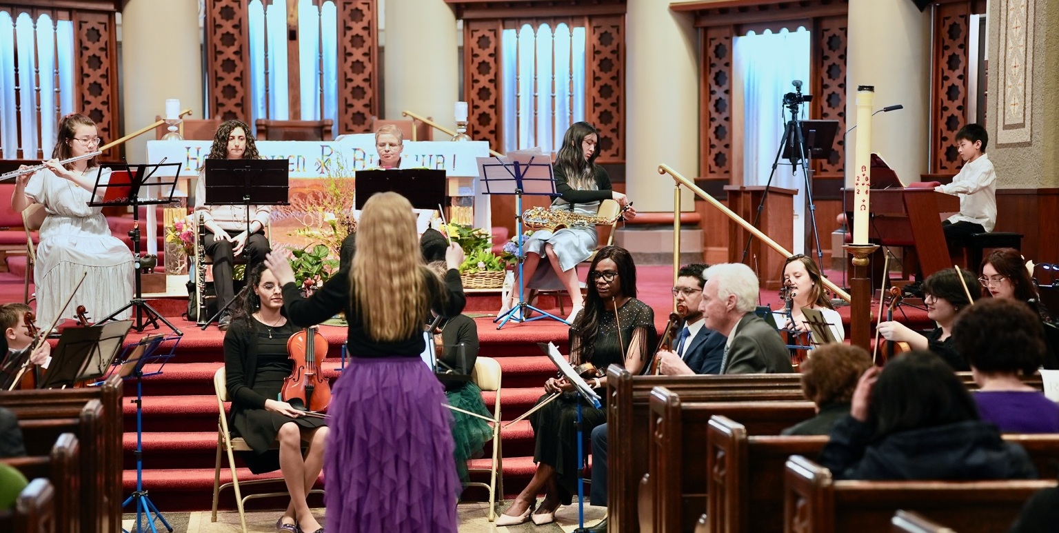 Olena Ponpon conducting an orchestra in a church sanctuary
