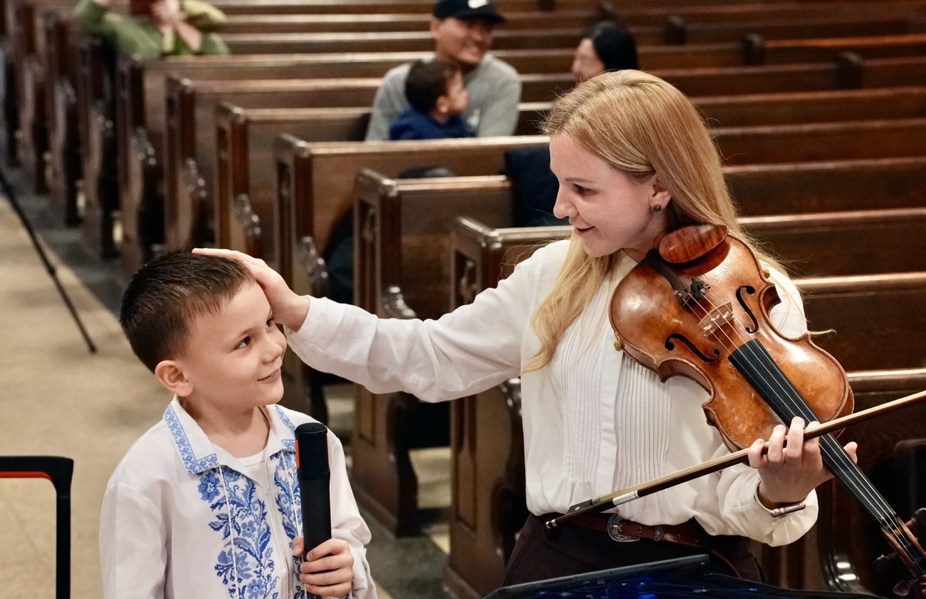 Olena Ponpon holding her violin and greeting a young performer